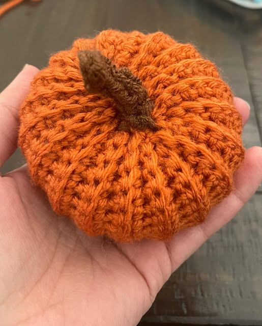 Orange crochet pumpkin held in a hand